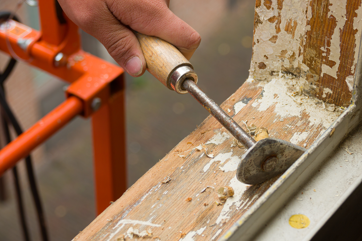 A painter removing old paint with a scraper in a Sunol, CA home